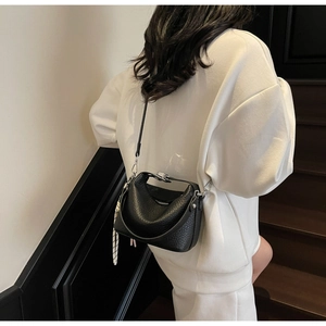 Detail of minimalist black pebbled leather handbag with silver lock and structured handle