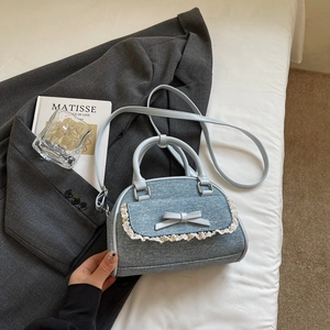Detail of light blue denim handbag featuring delicate lace trim and a stylish bow ornament