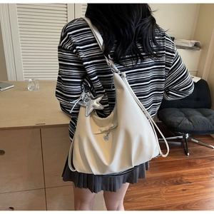 Detail of white half-moon bag with bow decoration, heart pendant and star charm