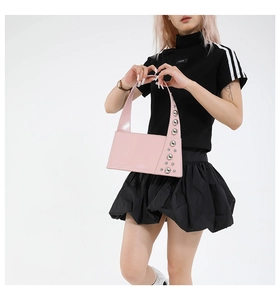 Pink patent leather shoulder bag with silver metal studs shown on a fashion model