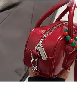 Close-up of smooth silver zipper and glossy red patent leather finish on handbag