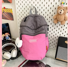Dettaglio dello zaino casual in nylon grigio e rosa con pendente in peluche bianco