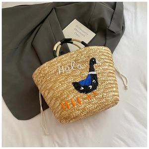 Close-up of handmade straw bag featuring cartoon duck embroidery and Halo text detail