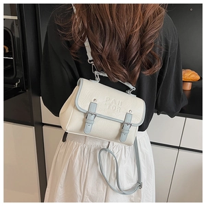 Detail shot of the embossed PAN TOR logo on a vintage cream crossbody bag with blue trim