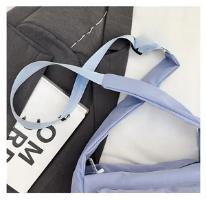 Close-up of the wide padded shoulder strap and light blue nylon crossbody bag