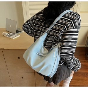 Close-up of light blue shoulder bag with elegant pleated design and bow decoration