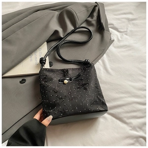 Close-up of black bow bucket bag featuring floral embroidery and elegant pearl pendant
