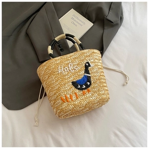 Detail of hand-woven straw bag with duck embroidery and stylish drawstring closure
