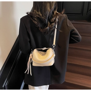 Detail view of cream lychee texture crossbody bucket bag worn on black oversized blazer