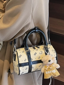Fashionable cream Boston bag with cartoon bear pattern and plush charm on trench coat