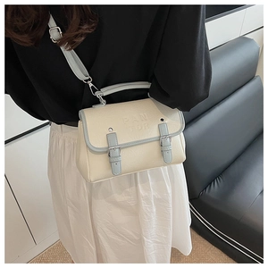 Retro cream white embossed leather messenger bag worn on shoulder by model in modern room