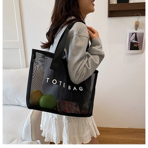 Détail d'un sac cabas en filet noir avec logo blanc montrant un grand espace intérieur