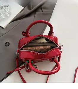 Interior view showing capacity of the red patent leather satchel with wallet and phone