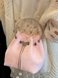 Pink drawstring bucket bag with silver butterfly buckle and pearl pendant on knit background
