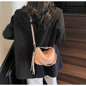 Detail view of pink lychee grain leather crossbody bag with silver hardware and tassel