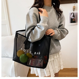 Détail d'un sac cabas en maille noire montrant la transparence avec fruits à l'intérieur