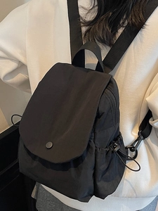 Minimalist black canvas drawstring backpack with flap closure and adjustable side pockets