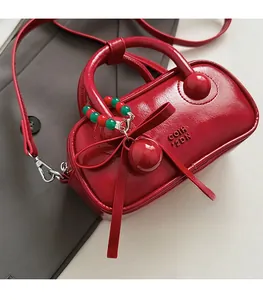 Detail of red patent leather pillow bag with cherry charm and leather bow ornament
