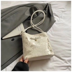 Detail of white bucket bag with butterfly print, bow decoration, and pearl accent