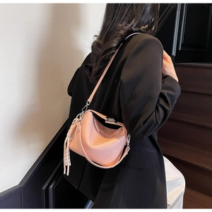 Detailed view of a pink pebbled leather handbag with knotted strap and silver hardware