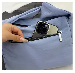 Close-up of the rear zipper pocket on a nylon crossbody bag holding a large smartphone
