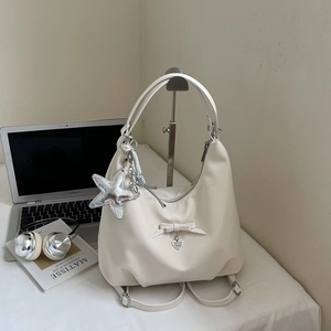 Detail of off-white hobo bag with a silver sequin star charm and heart pendant decorations