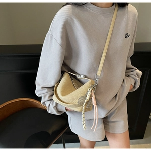 Detail of a creamy yellow lychee grain leather crossbody bag with a tennis racket charm