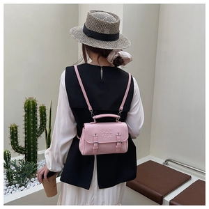 Detail of light pink PU leather backpack with PAN TOR embossed text on minimalist interior background