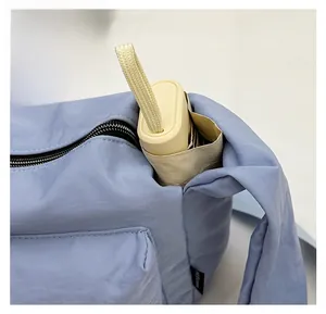Close-up of light blue nylon crossbody bag with side pocket for umbrella storage