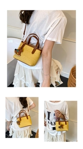 Detail view of yellow woven canvas handbag with brown leather handles and rocking horse charm