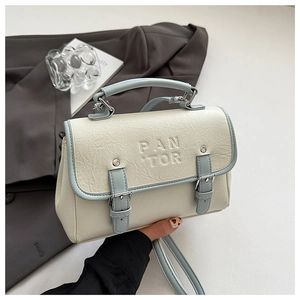 Detail of cream lychee texture bag with blue trim and silver buckles on a grey suit jacket