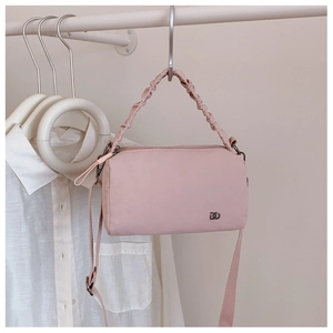 Détail du sac Boston rose clair avec poignée plissée et logo DD métallique sur un cintre