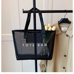 Détail d'un sac cabas en maille noire avec lettrage TOTE BAG blanc et sangles robustes
