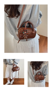 Close-up of brown PU leather boston bag with beaded charm and adjustable strap detail