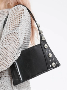 Fashionable black leather underarm bag with silver studs on textured knit background