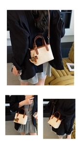 Detail of a woven beige handbag with brown leather trim shown in a fashion lifestyle shot