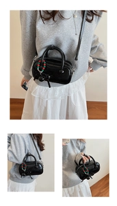 Detail view of black glossy patent leather mini bag with bead charms and bow