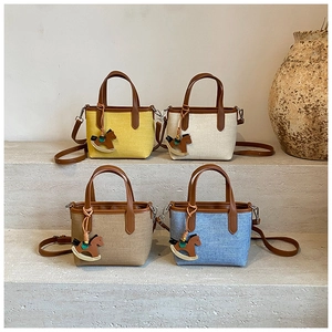 Mini canvas tote bags in four colors with leather straps on a stone staircase display