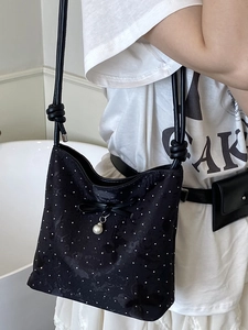 Borsa a secchiello nera scintillante con fiocco e ciondolo di perla sulla spalla