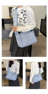 Macro detail of a light blue waterproof nylon crossbody bag with front zipper pocket
