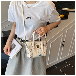 Détail d'un sac seau imprimé avec des graffitis colorés et une plaque logo dorée chic
