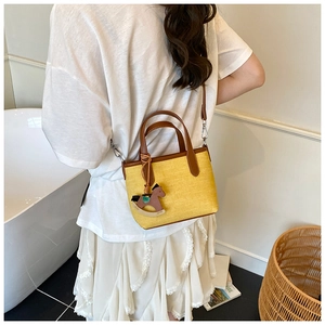 Detail of yellow canvas tote with brown leather trim and horse charm accessory