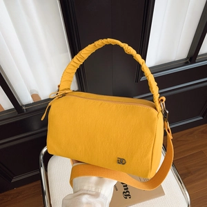 Détail du sac Boston en nylon jaune avec poignée froissée et logo métallique