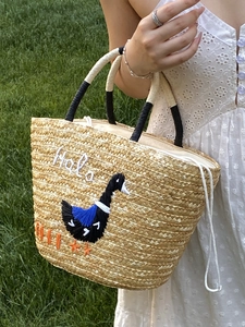 Straw tote bag with black bird embroidery and 'Halo' text for beach vacations