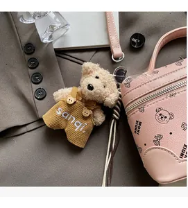 Detail of cute plush bear charm with yellow corduroy overalls on a pink bag strap