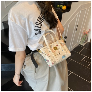 Détail du sac seau imprimé montrant des motifs graffiti colorés et ferrures dorées