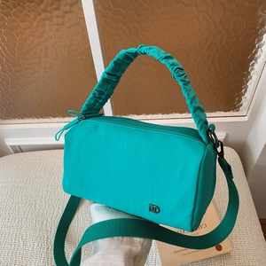 Détail du sac Boston en nylon vert sarcelle avec poignée plissée et large bandoulière