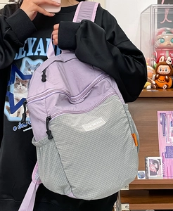 Dettaglio dello zaino in nylon a scacchi viola e grigio con tasca laterale a rete