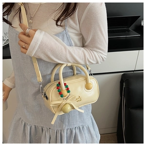 Detail of a mini cream white Boston bag with elegant bow pendant and gold logo