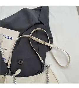 Detail of cream baguette bag with crocodile texture, silver chain and adjustable strap
